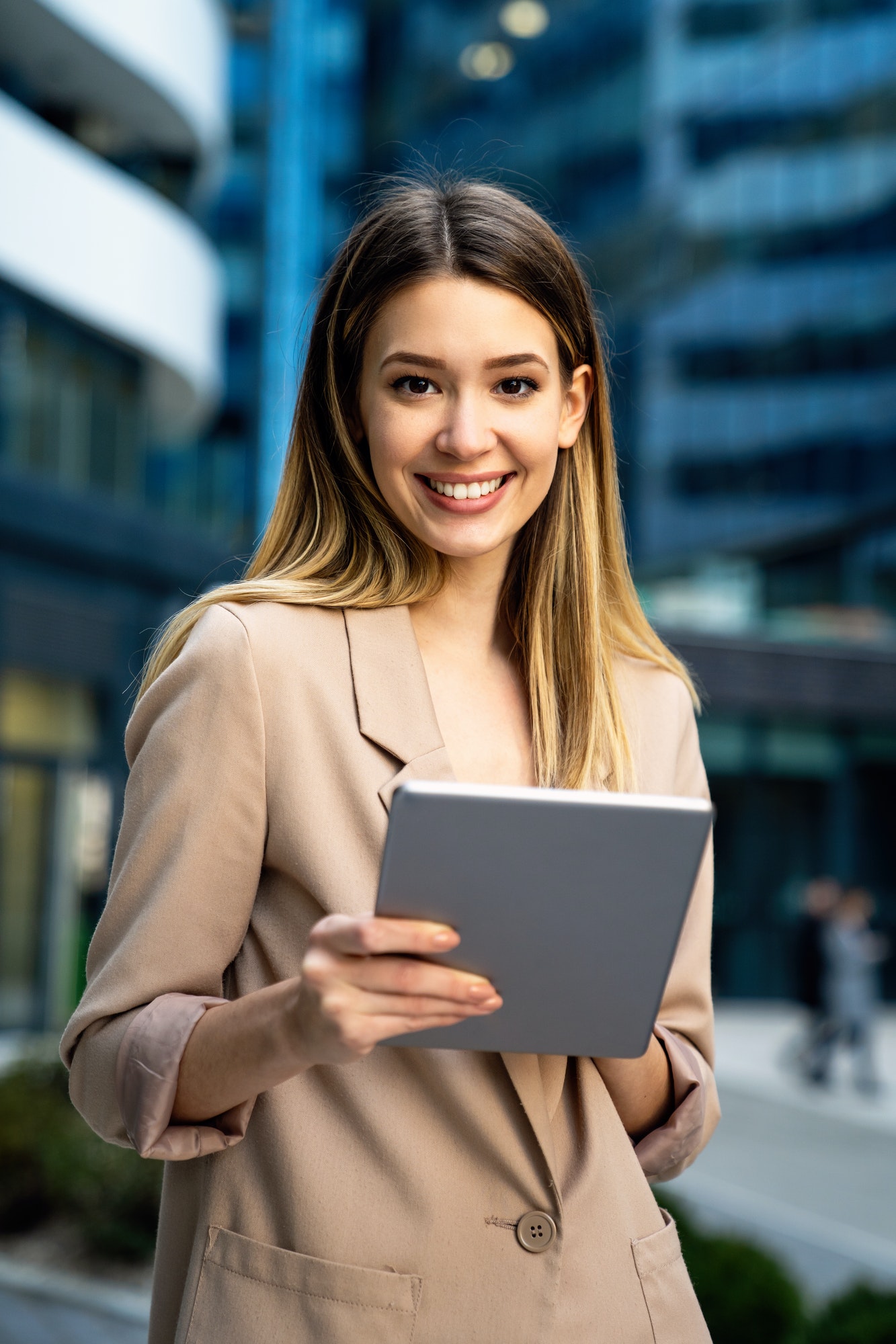 successful-businesswoman-using-a-digital-tablet-while-standing-in-front-of-business-building.jpg